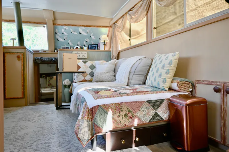 Slide: The Image of 1979 Uniflite Double Cabin interior with cozy seating, decorative pillows, and quilted blanket. - 24