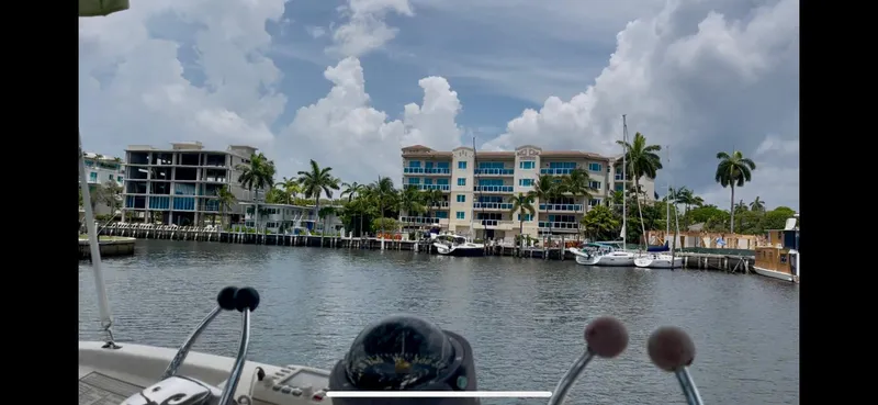 Slide: The Image of 1979 Uniflite Double Cabin boat view with waterfront buildings and palm trees under cloudy sky. - 30