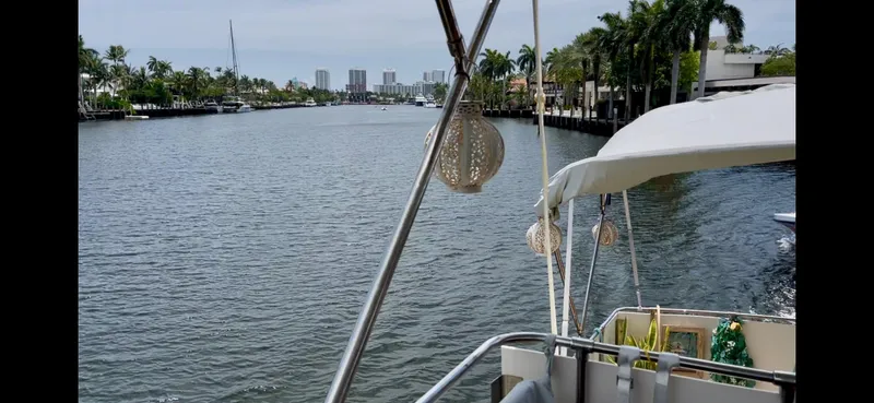Slide: The Image of 1979 Uniflite Double Cabin boat cruising on a scenic river with palm trees and city skyline. - 32
