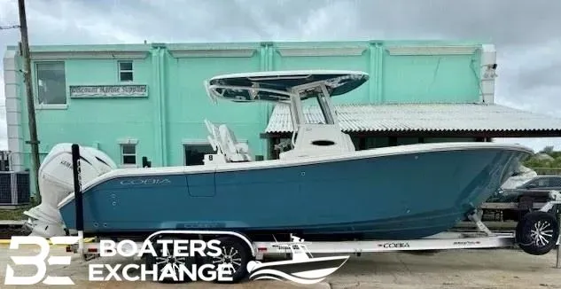 The Image of 2025 Cobia 265 Center Console boat on trailer in front of building. - 1