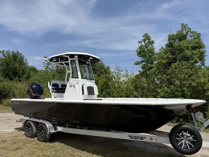 Slide: The Image of 2024 Tidewater 2410 Bay Max boat on trailer, parked outdoors with trees in background. - 1