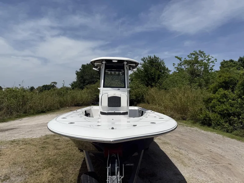 Slide: The Image of 2024 Tidewater 2410 Bay Max boat on a trailer, surrounded by greenery under a blue sky. - 35