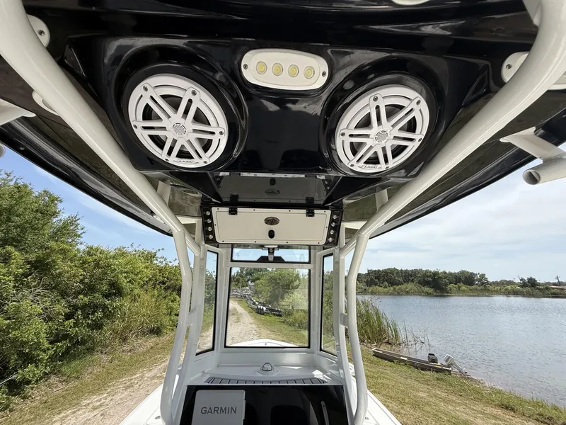 Slide: The Image of 2024 Tidewater 2410 Bay Max boat interior with speakers and Garmin equipment, near a scenic waterway. - 40