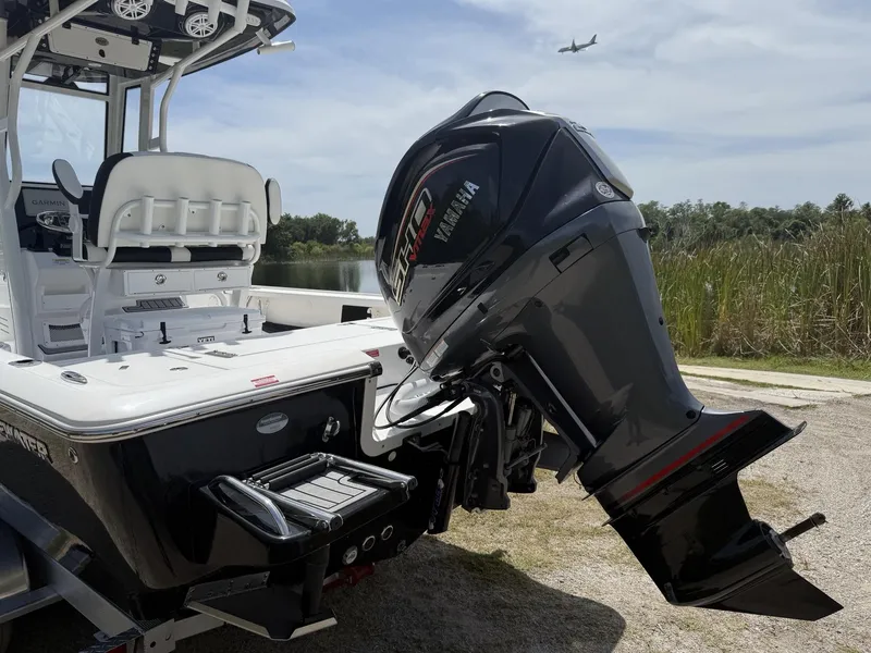 Slide: The Image of 2024 Tidewater 2410 Bay Max boat with Yamaha engine, parked near water, airplane overhead. - 5