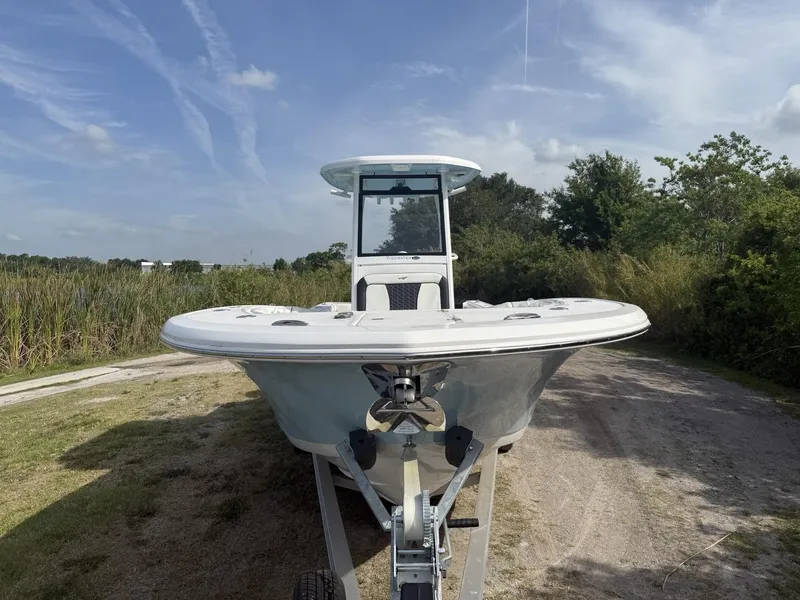 Slide: The Image of 2024 Tidewater 256 CC Adventure boat on trailer, parked on grassy path under blue sky. - 10