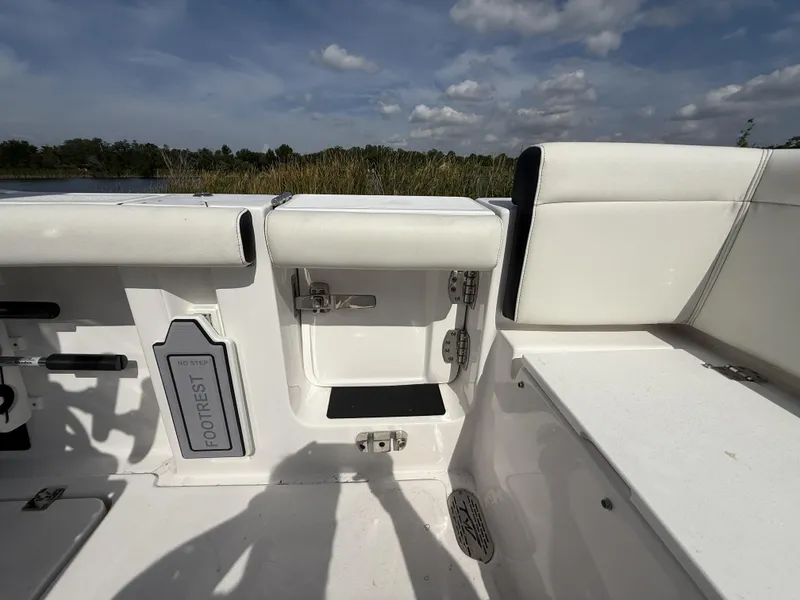 Slide: The Image of 2024 Tidewater 256 LXF boat interior with footrest and seating under a cloudy sky. - 16