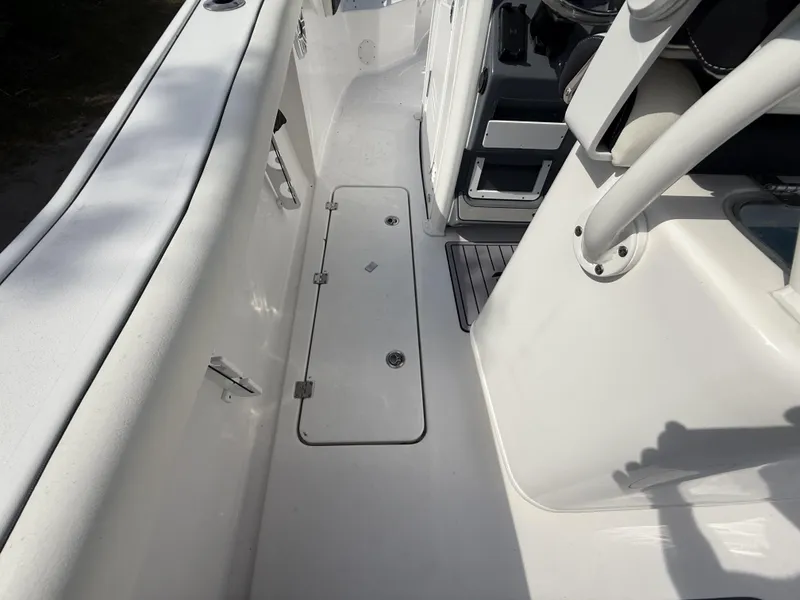 Slide: The Image of 2024 Tidewater 256 LXF boat interior, featuring sleek white deck and storage compartment. - 21