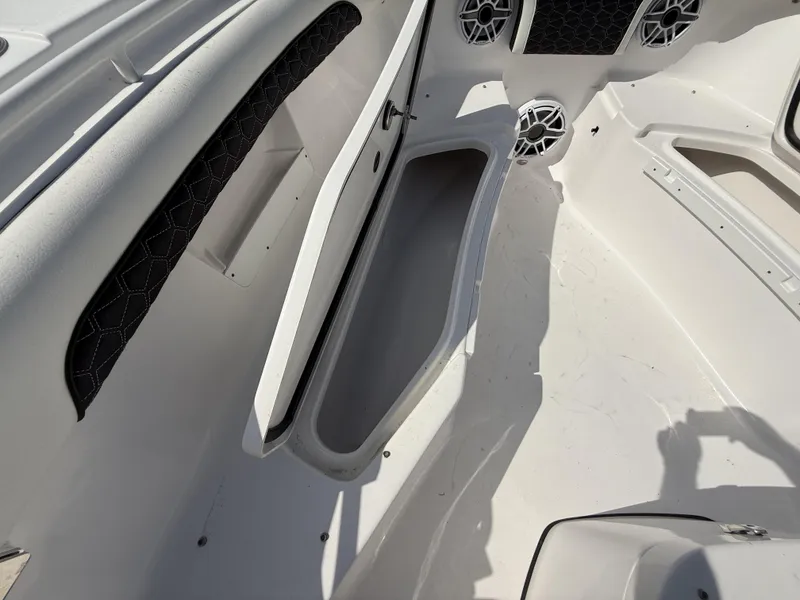 Slide: The Image of 2024 Tidewater 256 LXF boat interior with open storage compartment and speakers. - 22
