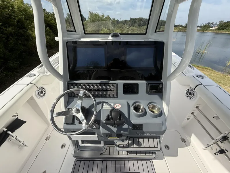 Slide: The Image of 2024 Tidewater 256 LXF boat console with steering wheel, dual screens, and cup holders. - 33