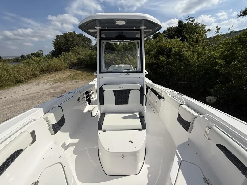 Slide: The Image of 2024 Tidewater 256 LXF boat interior with seating and console, surrounded by greenery. - 37