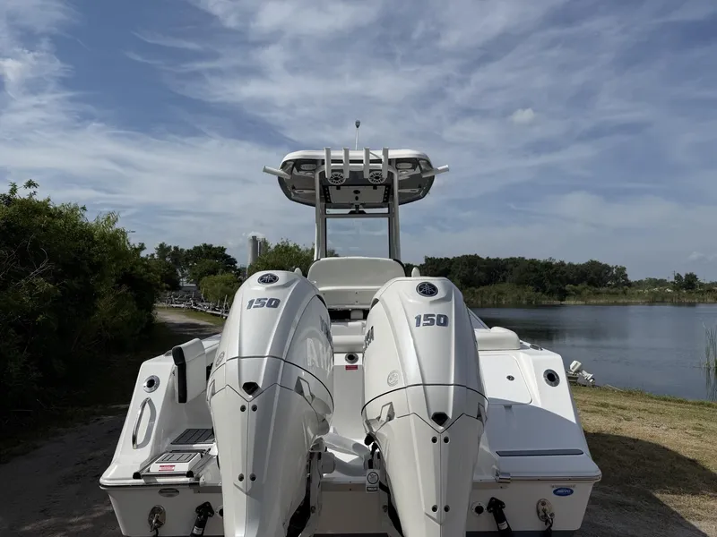 Slide: The Image of 2024 Tidewater 256 LXF boat with dual 150 engines by a lake. - 5