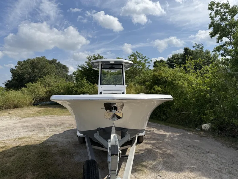 Slide: The Image of 2024 Tidewater 256 LXF boat on trailer, surrounded by greenery under a partly cloudy sky. - 7