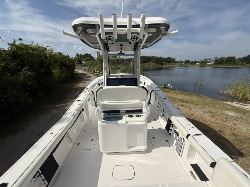 Slide: The Image of 2024 Tidewater 256 LXF boat interior with helm, near a serene lake. - 8