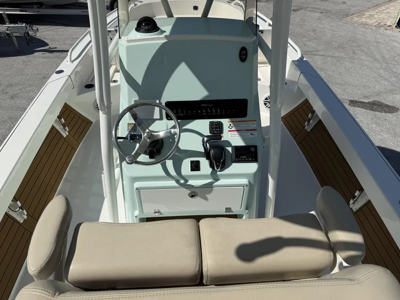 Slide: The Image of 2024 Pathfinder 2600 TRS boat console with steering wheel and controls, featuring beige seating. - 10