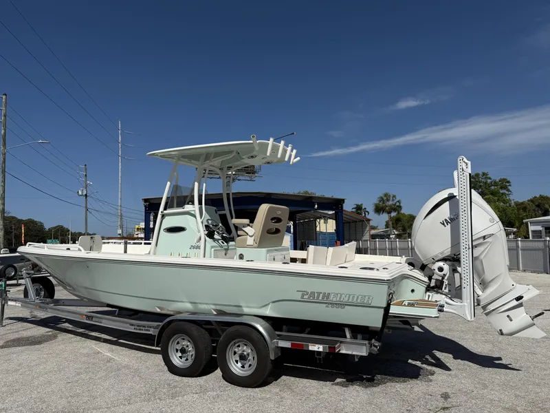Slide: The Image of 2024 Pathfinder 2600 TRS boat on trailer, parked outdoors under clear blue sky. - 3