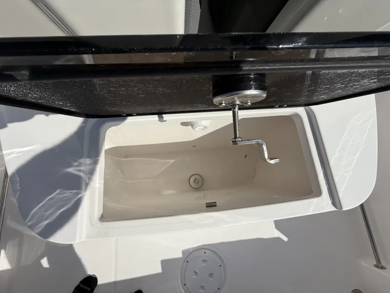 Slide: The Image of 2024 Aquasport 2300 CC boat storage compartment with open lid and handle. - 12