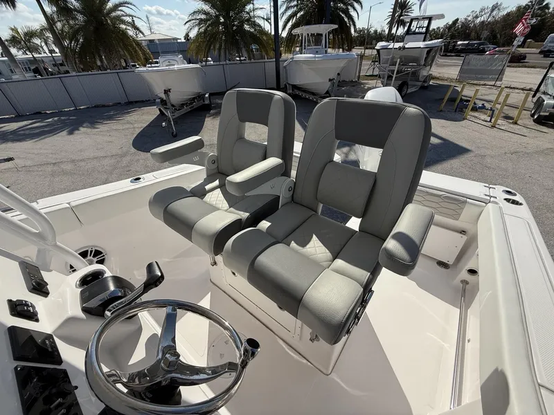 Slide: The Image of 2024 Aquasport 2300 CC boat interior with dual gray seats and steering wheel. - 13