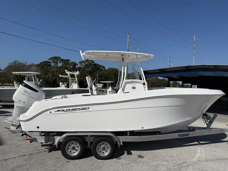 Slide: The Image of 2024 Aquasport 2300 CC boat on trailer, side view, clear sky background. - 23
