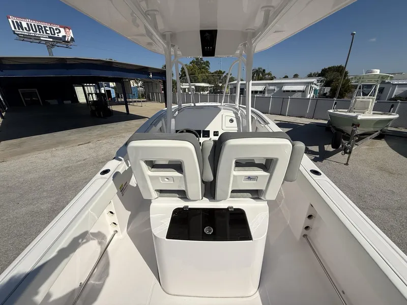Slide: The Image of 2024 Aquasport 2300 CC boat interior with seating and console, parked outdoors. - 26