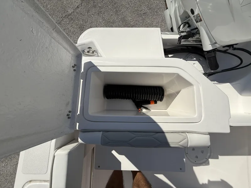 Slide: The Image of Open storage compartment on 2024 Aquasport 2300 CC boat, showing coiled hose inside. - 33