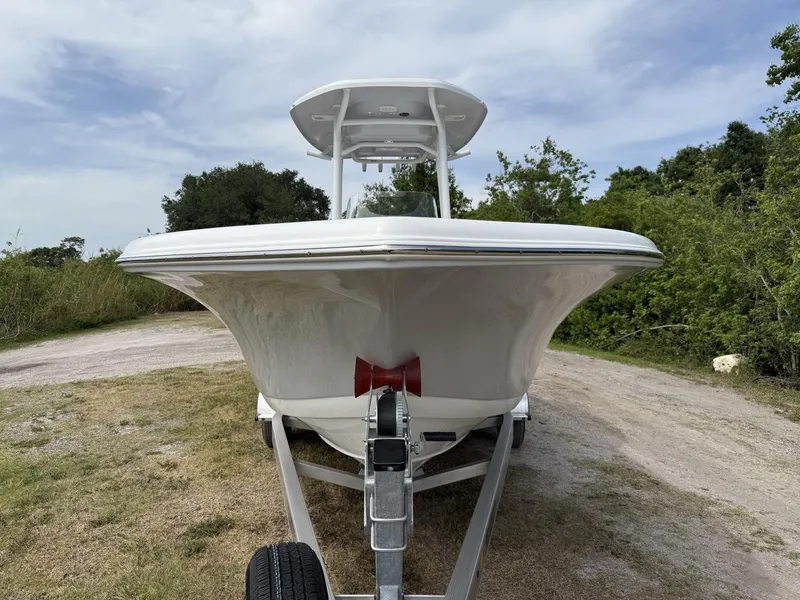 Slide: The Image of 2024 Tidewater 220 CC Adventure boat on trailer, parked on grassy area with trees. - 18