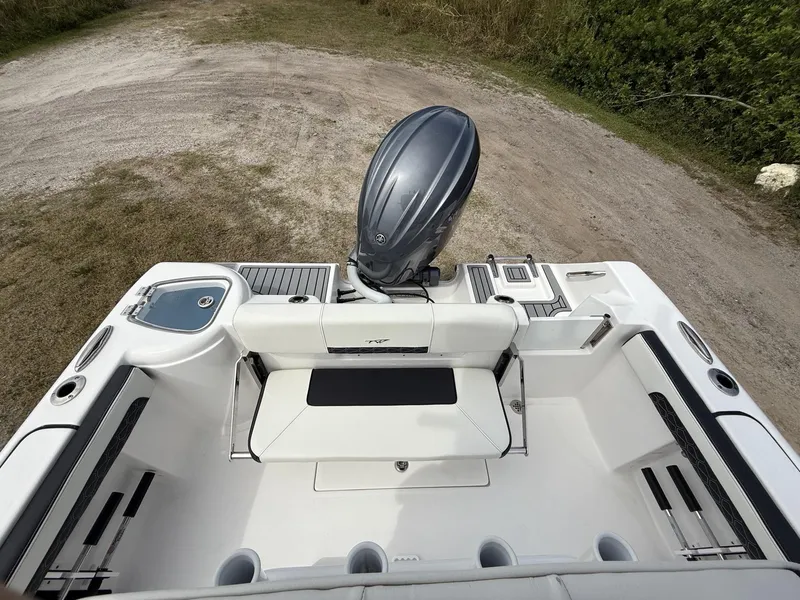 Slide: The Image of 2024 Tidewater 220 CC Adventure boat interior with seating and motor, parked on grassy terrain. - 29