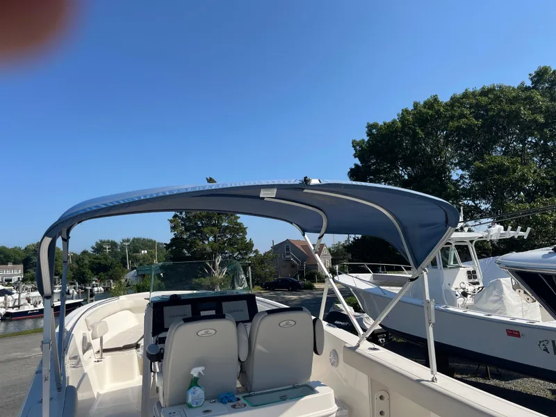 Slide: The Image of 2022 Sailfish 320 CC boat with blue canopy docked at marina. - 11