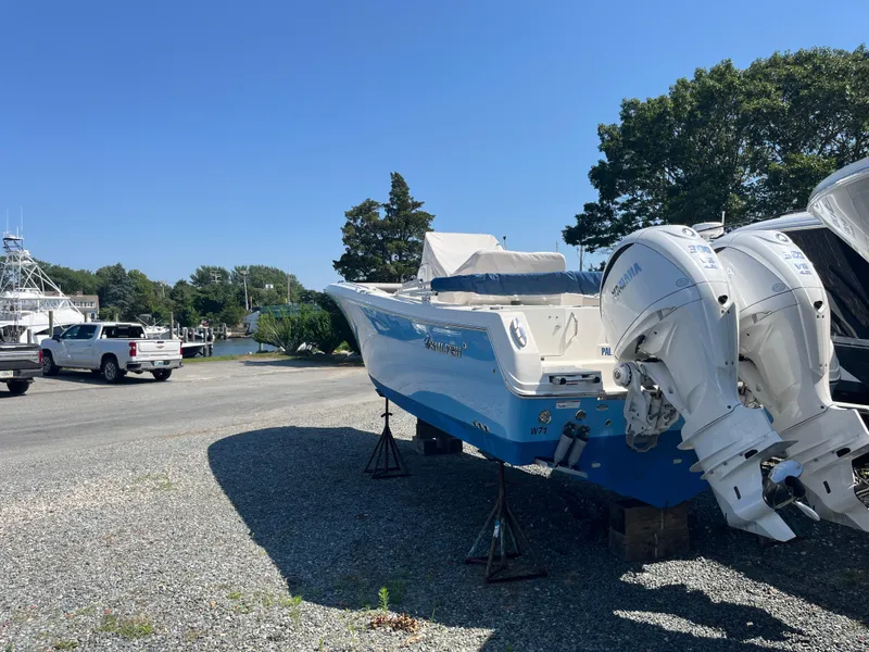 Slide: The Image of 2022 Sailfish 320 CC boat with twin outboard engines on a gravel lot. - 12