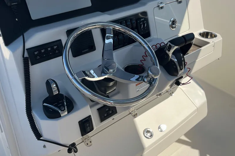 Slide: The Image of 2022 Sailfish 320 CC boat helm with steering wheel and control panel. - 18