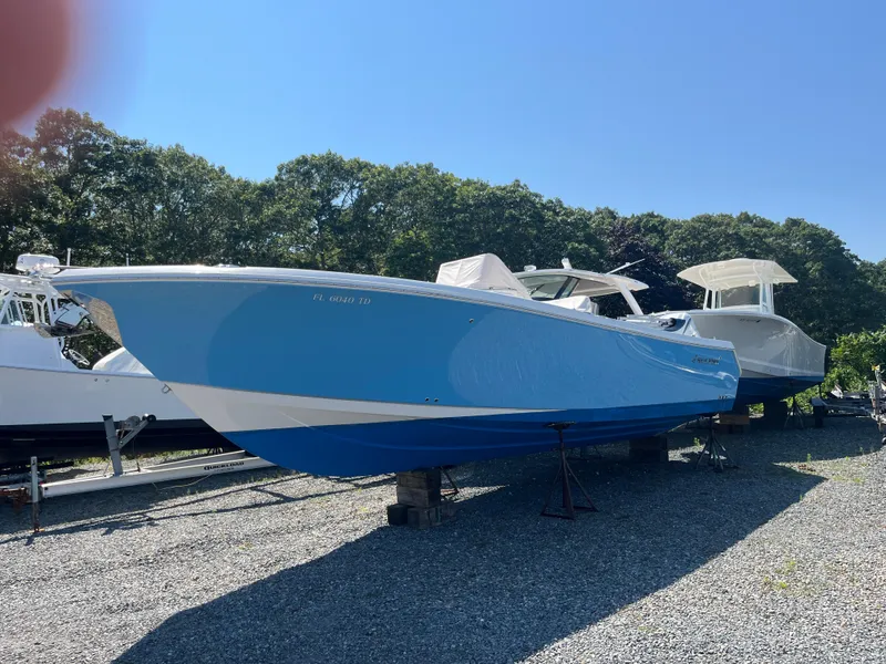 Slide: The Image of 2022 Sailfish 320 CC boat in blue, parked on gravel lot. - 3