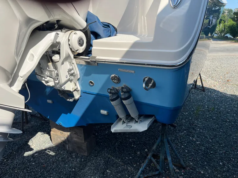 Slide: The Image of 2022 Sailfish 320 CC boat stern on a stand, showing engine mount and trim tabs. - 5