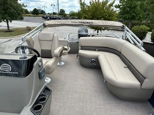 Slide: The Image of 2024 Sun Tracker Bass Buggy 18 DLX pontoon boat interior with plush seating and helm. - 3