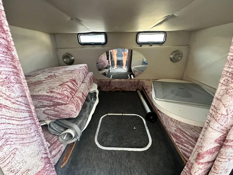 Slide: The Image of 1994 Crownline 250 CR cabin interior with patterned cushions and small windows. - 15