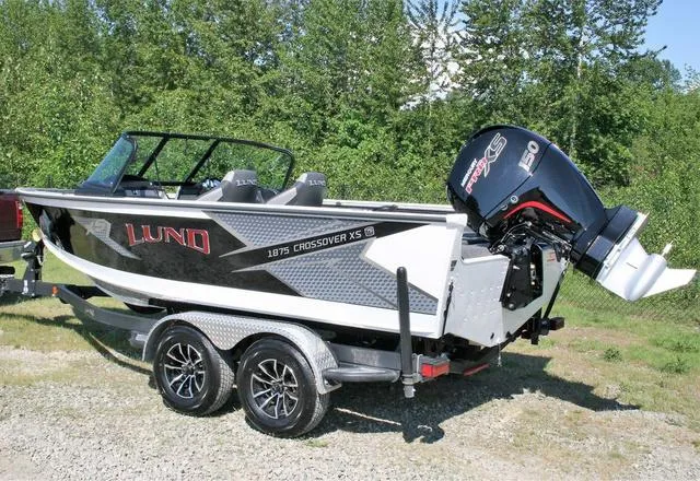 Slide: The Image of 2024 Lund 1875 Crossover XS Sport boat on a trailer, parked outdoors. - 3