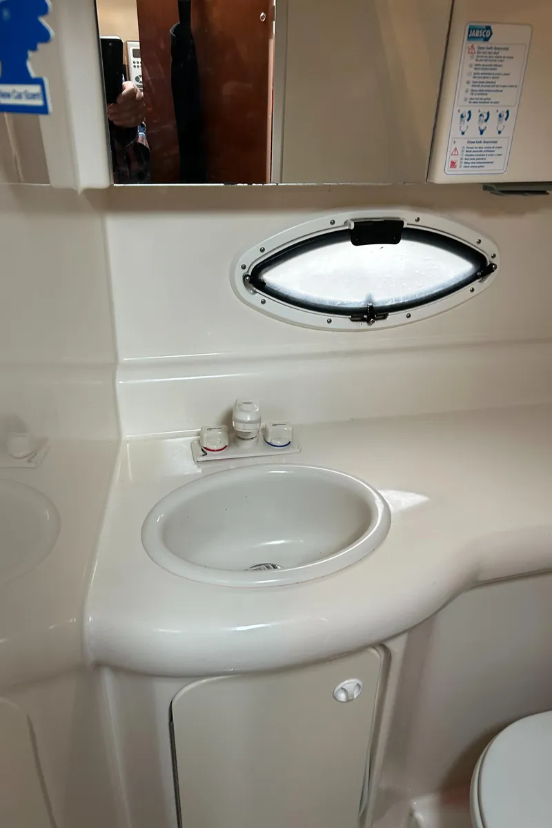 Slide: The Image of 2007 Maxum 2400 SE boat bathroom with sink, mirror, and porthole window. - 23