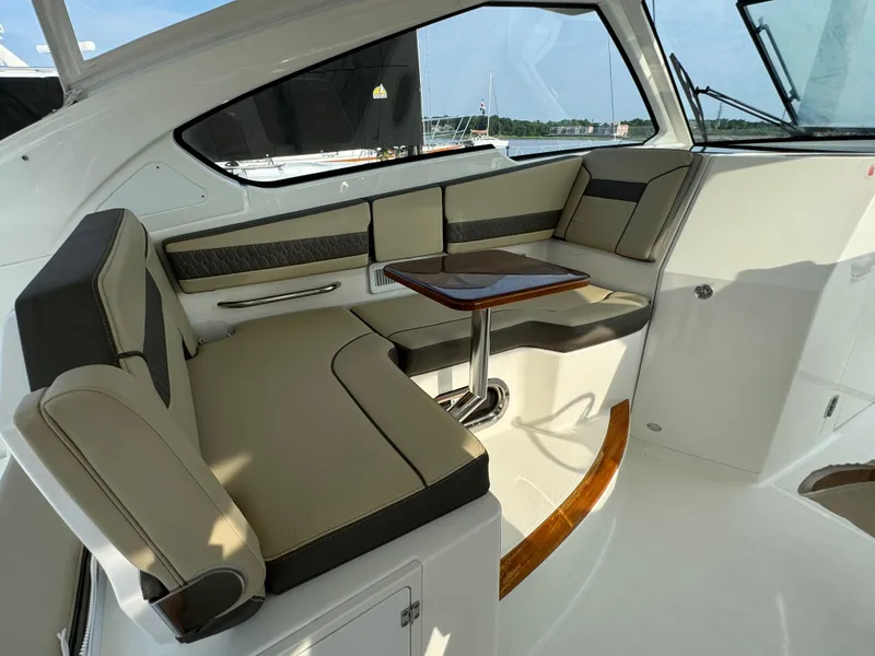 Slide: The Image of Interior seating area of 2021 Pursuit DC 365 boat with cushioned seats and a wooden table. - 13