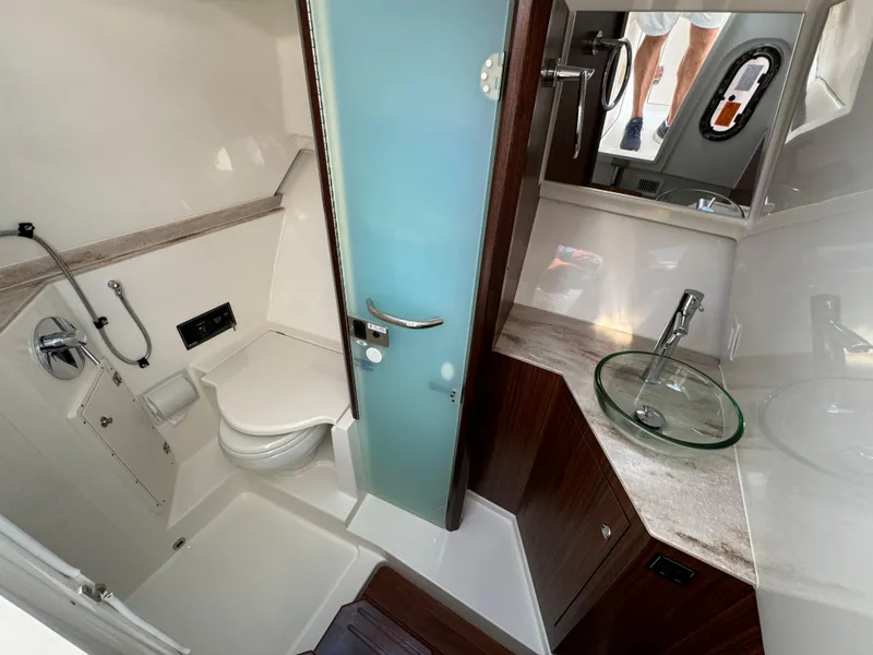 Slide: The Image of 2021 Pursuit DC 365 boat bathroom with modern fixtures and glass sink. - 17