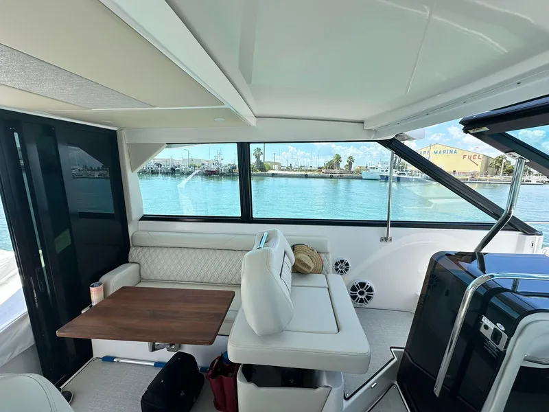 Slide: The Image of Interior of 2023 Regal Grande Coupe yacht with seating and table, overlooking marina. - 7