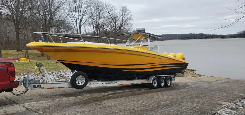 Slide: The Image of Yellow 2004 Fountain 38 Sportfish CC boat on trailer by a lake. - 2