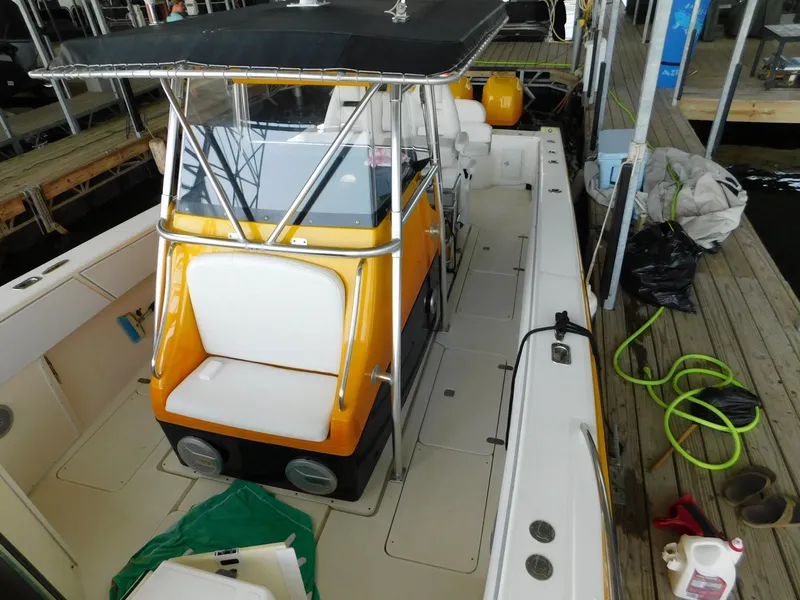 Slide: The Image of 2004 Fountain 38 Sportfish CC boat with orange console and white seating, docked with equipment nearby. - 27