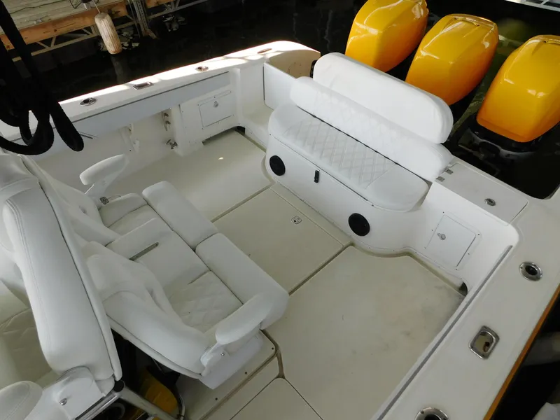 Slide: The Image of 2004 Fountain 38 Sportfish CC boat interior with white seating and yellow engine covers. - 32