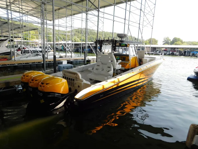 Slide: The Image of 2004 Fountain 38 Sportfish CC boat with triple outboard engines docked under a canopy. - 40