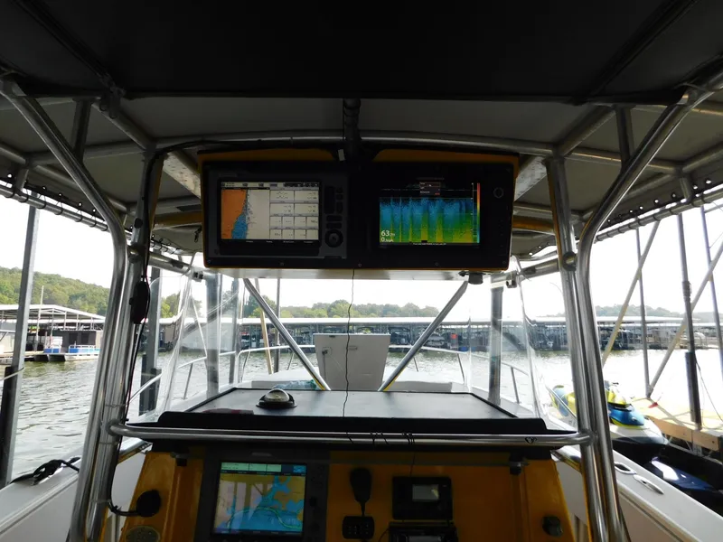 Slide: The Image of 2004 Fountain 38 Sportfish CC boat cockpit with navigation screens and marina view. - 6