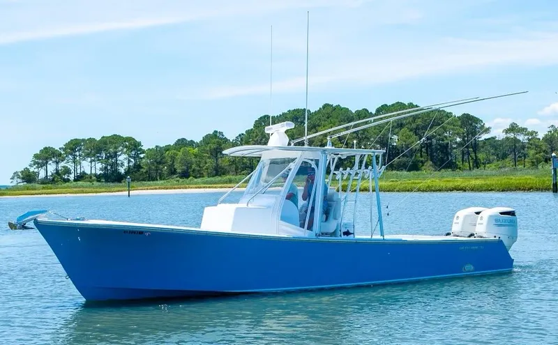 Slide: The Image of Custom 31 2020 model blue fishing boat on calm water with trees in the background. - 12