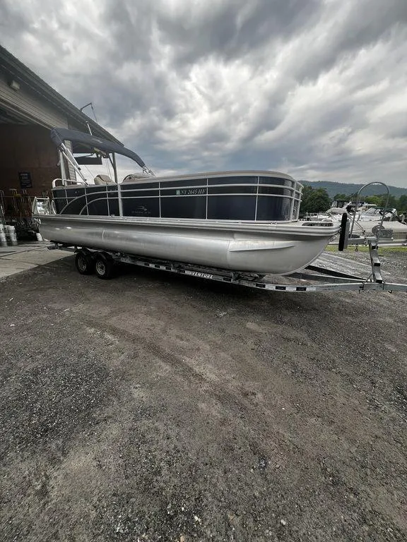 The Image of 2019 Bennington 25 SPDXP pontoon boat on a trailer under cloudy skies. - 1