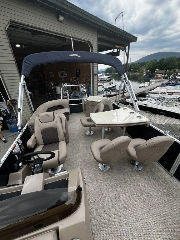 Slide: The Image of 2019 Bennington 25 SPDXP pontoon boat with spacious seating and table, docked at a marina. - 5