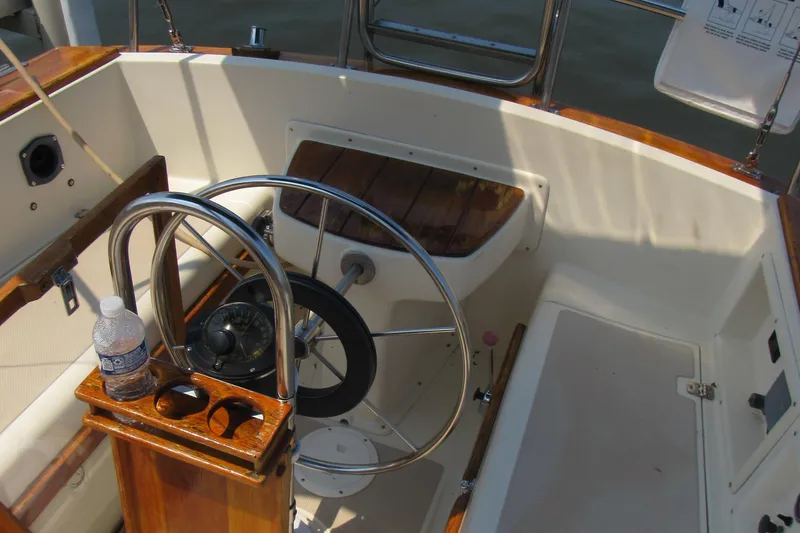 Slide: The Image of 1987 Island Packet 31 sailboat cockpit with steering wheel and wooden accents. - 14