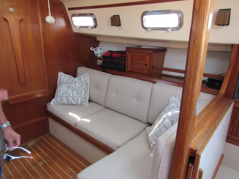Slide: The Image of Interior of 1987 Island Packet 31 sailboat with cushioned seating and wooden accents. - 3
