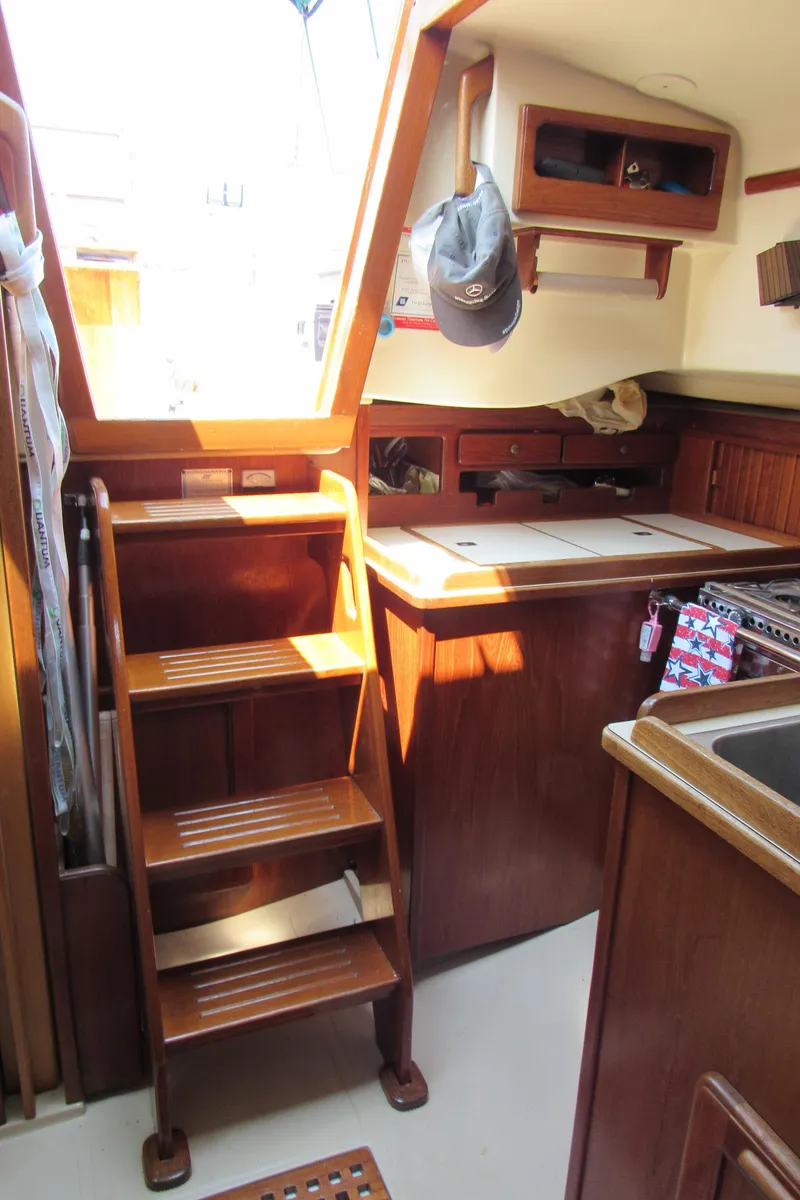 Slide: The Image of 1987 Island Packet 31 yacht interior with wooden stairs and compact kitchen area. - 9