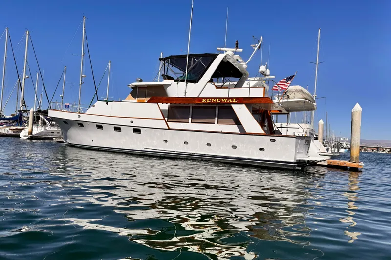 The Image of 1976 Nordlund 60 Motoryacht docked in marina, clear blue sky, calm water. - 0